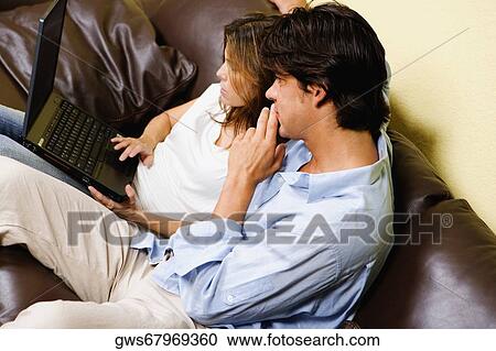 Mid adult couple using a laptop with a mid adult man sitting beside her View Large Photo Image Stock Image - Mid adult couple using a laptop with a mid adult man sitting beside her. Fotosearch