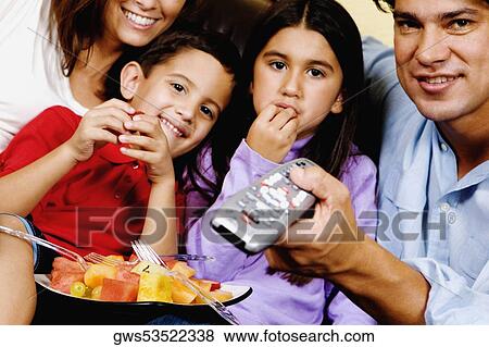 Mid adult couple with their children watching television View Large Photo Image Stock Photo - Mid adult couple with their children watching television. Fotosearch