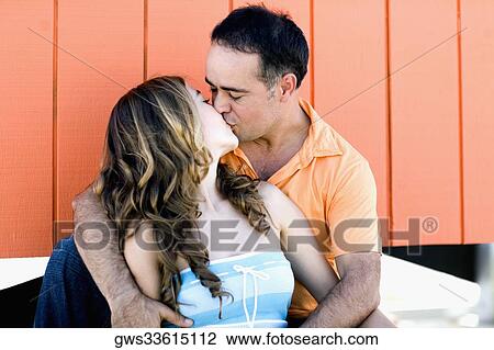Mid adult man and a young woman kissing each other View Large Photo Image Stock Image - Mid adult man and a young woman kissing each other. Fotosearch