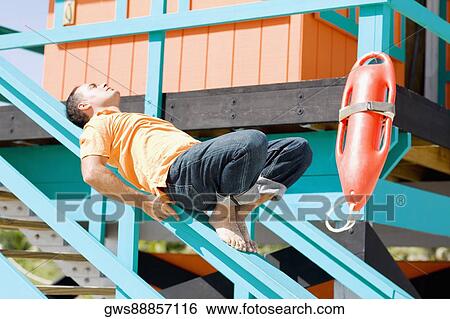 Mid adult man lying on the hand rail of a lifeguard hut View Large Photo Image Stock Photograph - Mid adult man lying on the hand rail of a lifeguard hut. Fotosearch