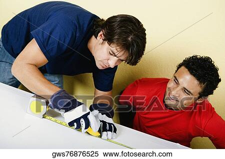 Mid adult man measuring a board with a measuring tape and a young man looking at him View Large Photo Image Stock Photography - Mid adult man measuring a board with a measuring tape and a young man looking at him. Fotosearch