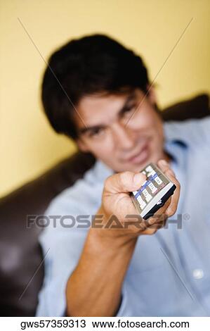 Stock Image - Mid adult man operating a remote control. Fotosearch
