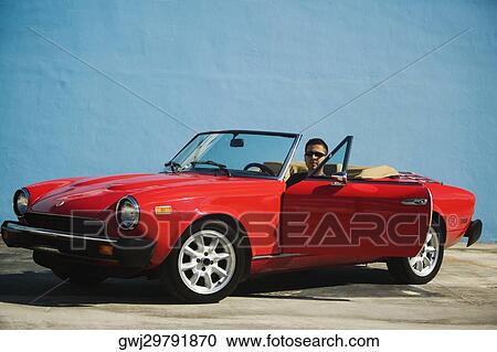 Stock Image - Mid adult man sitting in a car. Fotosearch