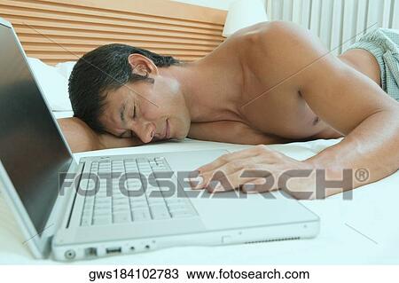 Mid adult man sleeping near a laptop View Large Photo Image Stock Image - Mid adult man sleeping near a laptop. Fotosearch