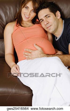 Picture - Mid adult man touching pregnant young woman's abdomen. Fotosearch