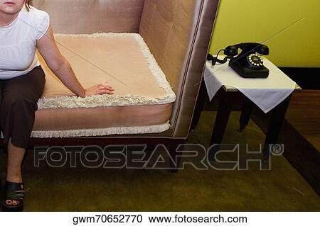 Stock Image - Mid adult woman sitting in an armchair. Fotosearch