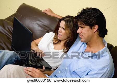 Mid adult woman using a laptop with a mid adult man sitting beside her View Large Photo Image Stock Photograph - Mid adult woman using a laptop with a mid adult man sitting beside her. Fotosearch