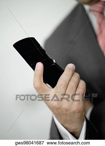 Mid section view of a businessman holding a mobile phone View Large Photo Image Stock Photo - Mid section view of a businessman holding a mobile phone. Fotosearch