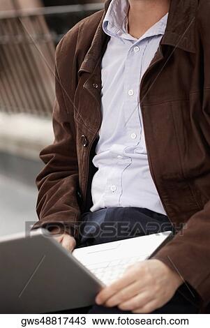 Mid section view of a businessman using a laptop View Large Photo Image Stock Image - Mid section view of a businessman using a laptop. Fotosearch