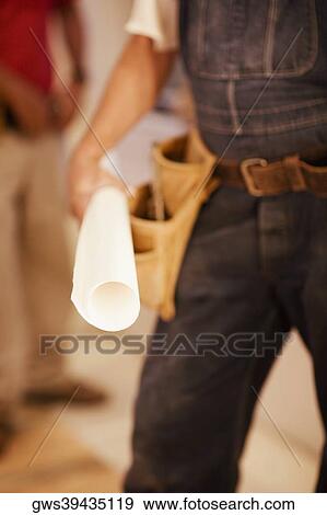 Mid section view of a male architect holding a blueprint View Large Photo Image Stock Photo - Mid section view of a male architect holding a blueprint. Fotosearch