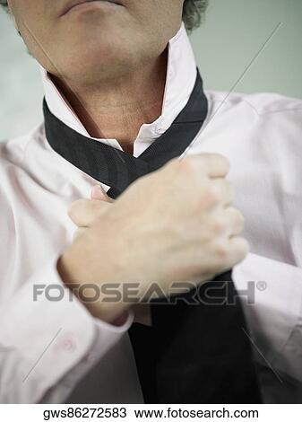 Mid section view of a man adjusting his tie View Large Photo Image Stock Image - Mid section view of a man adjusting his tie. Fotosearch