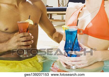 Mid section view of a man and woman holding a glass View Large Photo Image Stock Image - Mid section view of a man and woman holding a glass. Fotosearch
