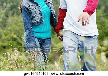 Mid section view of a man and woman walking in a field View Large Photo Image Stock Photograph - Mid section view of a man and woman walking in a field. Fotosearch