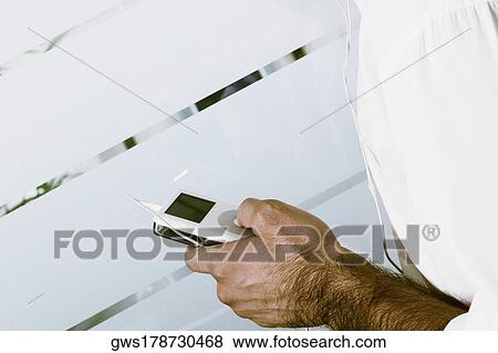 Stock Photo - Mid section view of a man holding a MP3 player. Fotosearch