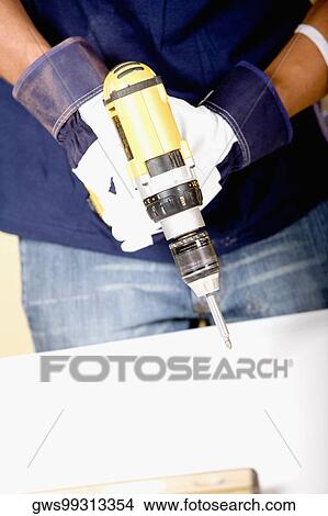 Mid section view of a man holding a drill machine View Large Photo Image Picture - Mid section view of a man holding a drill machine. Fotosearch