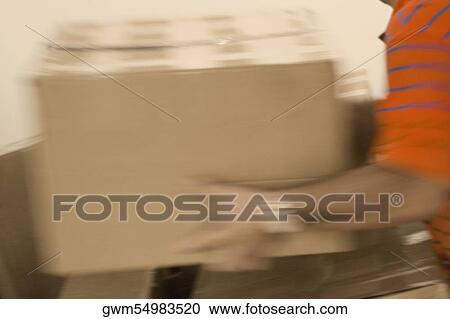 Stock Image - Mid section view of a man holding a cardboard box. Fotosearch