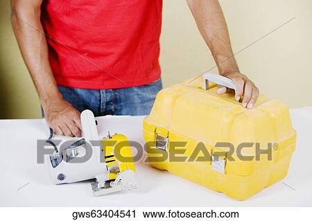 Mid section view of a man holding a circular saw and a tool box View Large Photo Image Stock Image - Mid section view of a man holding a circular saw and a tool box. Fotosearch