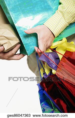 Stock Image - Mid section view of a man holding shopping bags. Fotosearch