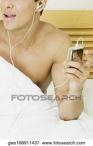 Mid section view of a man listening to an MP3 player View Large Photo Image Stock Photo - Mid section view of a man listening to an MP3 player. Fotosearch
