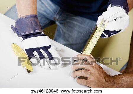 Mid section view of a man measuring with a measuring tape and a man's hand helping him View Large Photo Image Stock Photograph - Mid section view of a man measuring with a measuring tape and a man's hand helping him. Fotosearch