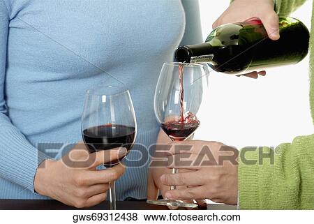 Mid section view of a man standing with a woman pouring wine into a wine glass View Large Photo Image Stock Photo - Mid section view of a man standing with a woman pouring wine into a wine glass. Fotosearch