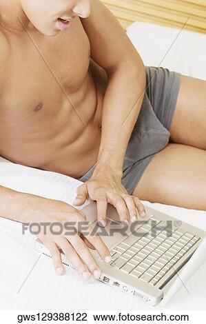 Mid section view of a man using a laptop View Large Photo Image Stock Image - Mid section view of a man using a laptop. Fotosearch