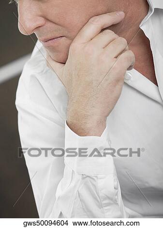 Mid section view of a mature man with his hand on his chin View Large Photo Image Picture - Mid section view of a mature man with his hand on his chin. Fotosearch