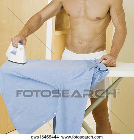 Mid section view of a mid adult man ironing a shirt on an ironing board View Large Photo Image Picture - Mid section view of a mid adult man ironing a shirt on an ironing board. Fotosearch