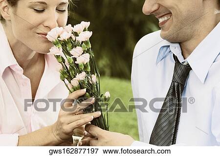 Mid section view of a mid adult man giving flowers to a young woman View Large Photo Image Stock Photo - Mid section view of a mid adult man giving flowers to a young woman. Fotosearch