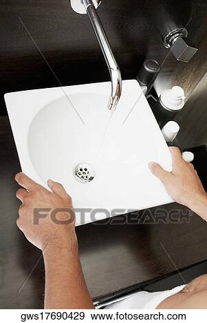 Stock Photo - Mid section view of a person standing in front of a bathroom sink. Fotosearch
