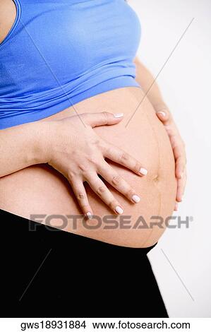 Mid section view of a pregnant woman touching her abdomen View Large Photo Image Picture - Mid section view of a pregnant woman touching her abdomen. Fotosearch