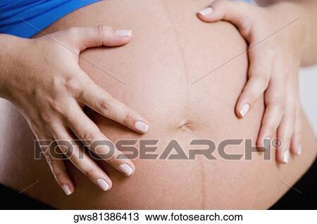 Mid section view of a pregnant woman touching her abdomen View Large Photo Image Stock Image - Mid section view of a pregnant woman touching her abdomen. Fotosearch