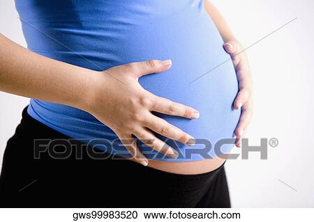 Mid section view of a pregnant woman touching her abdomen View Large Photo Image Stock Image - Mid section view of a pregnant woman touching her abdomen. Fotosearch