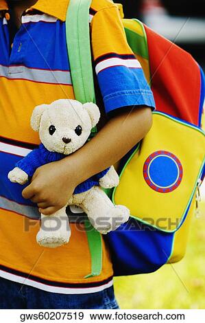 Stock Photo - Mid section view of a schoolboy carrying a school bag and a teddy bear. Fotosearch