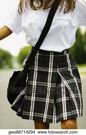 Picture - Mid section view of a schoolgirl walking on the road. Fotosearch