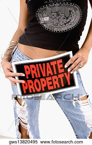 Stock Photography - Mid section view of a woman holding a Private Property sign in front of her crotch. Fotosearch