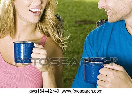 Mid section view of a young couple holding coffee cups View Large Photo Image Stock Photo - Mid section view of a young couple holding coffee cups. Fotosearch