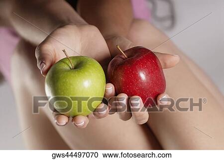 Mid section view of a young woman holding two apples View Large Photo Image Stock Image - Mid section view of a young woman holding two apples. Fotosearch