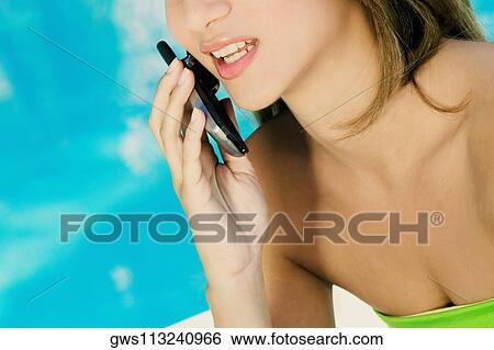 Mid section view of a young woman talking on a mobile phone View Large Photo Image Stock Photograph - Mid section view of a young woman talking on a mobile phone. Fotosearch