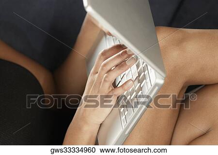 Mid section view of a young woman using a laptop View Large Photo Image Stock Image - Mid section view of a young woman using a laptop. Fotosearch