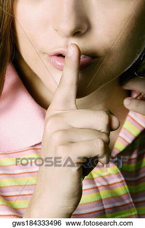 Mid section view of a young woman with a finger on her lips View Large Photo Image Stock Photograph - Mid section view of a young woman with a finger on her lips. Fotosearch