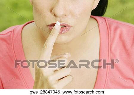 Mid section view of a young woman with a finger on her lips View Large Photo Image Stock Photography - Mid section view of a young woman with a finger on her lips. Fotosearch