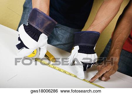 Mid section view of two men measuring with a measuring tape View Large Photo Image Stock Photograph - Mid section view of two men measuring with a measuring tape. Fotosearch