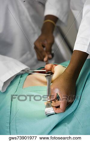Stock Photo - Mid section view of two surgeons performing surgery. Fotosearch