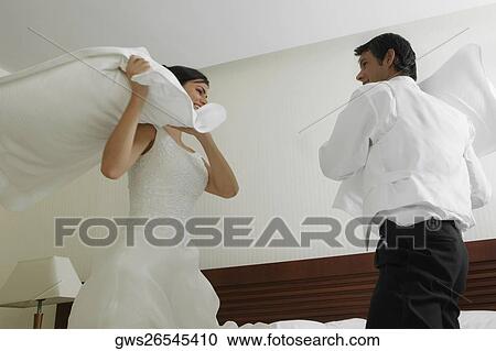 Newlywed couple having a pillow fight on the bed View Large Photo Image Stock Image - Newlywed couple having a pillow fight on the bed. Fotosearch