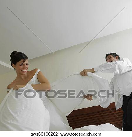 Newlywed couple having a pillow fight on the bed View Large Photo Image Stock Image - Newlywed couple having a pillow fight on the bed. Fotosearch
