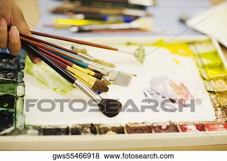 Stock Photo - Person's hand holding paint brushes. Fotosearch
