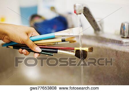 Person's hand washing paint brushes under a faucet View Large Photo Image Stock Photo - Person's hand washing paint brushes under a faucet. Fotosearch