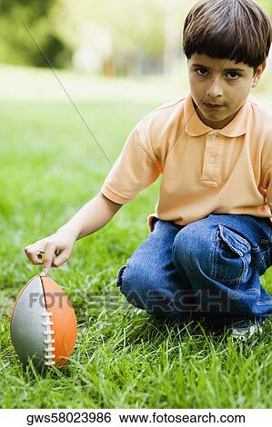 Portrait of a boy crouching with his finger on a rugby ball View Large Photo Image Stock Photograph - Portrait of a boy crouching with his finger on a rugby ball. Fotosearch