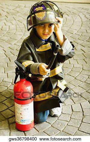 Portrait of a boy dressed as a firefighter and holding a fire extinguisher View Large Photo Image Stock Image - Portrait of a boy dressed as a firefighter and holding a fire extinguisher. Fotosearch